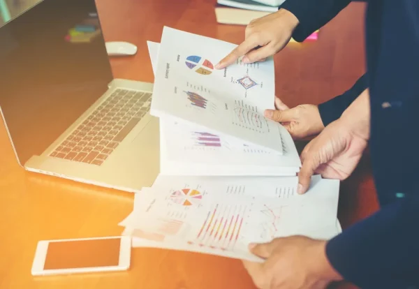 Business professionals reviewing quotations, reports, and analytics on a laptop using quotation management software solutions in Abu Dhabi to improve sales efficiency.